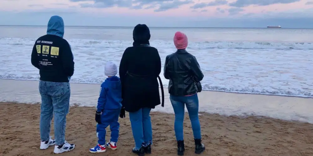 Four people standing at the beach looking out towards the ocean