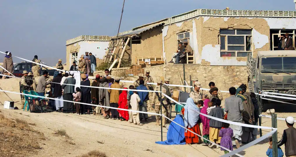 Villagers line up with army tanks